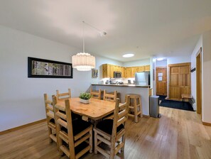 A modern kitchen with wooden cabinets, a central island, and a dining area with a wooden table and chairs. - Keystone Ski Retreat | Deck w/ Views + Hot Tubs (Keystone)
