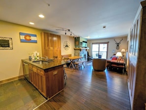 Une cuisine spacieuse avec des meubles en bois, une cheminée en pierre et un coin repas équipé d’une banquette.
