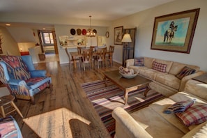A spacious living room with a large sofa, a dining table, and a patterned rug.