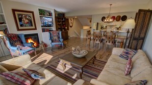 Un salon chaleureux avec une cheminée, des sièges confortables et un coin repas.