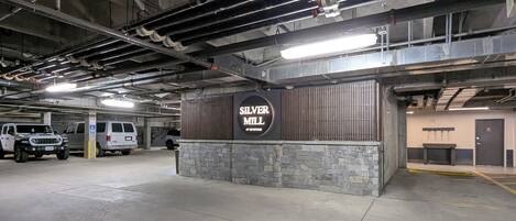 An underground parking garage with a sign for 'Silver Mill' and a row of parked vehicles.