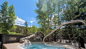 A hot tub with a stone wall and a sign indicating a maximum occupancy of 6 people. - Cozy Summer Retreat – Views, Hot Tub & River Run (Keystone)