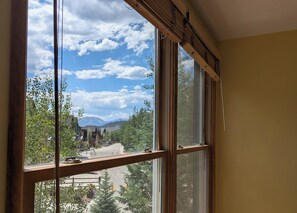 A room with a large window overlooking a street with buildings and trees. - Cozy Winter Retreat – Views, Hot Tub & River Run (Keystone)