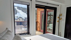 A bedroom with a large window overlooking a snowy mountain and a building. - Ultra-Luxury Penthouse | 100Yds to Slopes (Keystone)