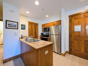 A modern kitchen with wooden cabinets, stainless steel appliances, and a built-in island with a sink.