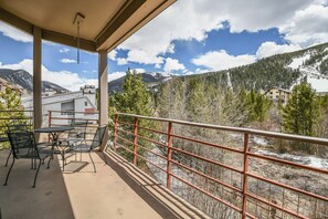 A balcony with a table and chairs, overlooking a mountainous landscape with a building in the background. - Family-Friendly | Walk to Lifts, Pool/Hot Tub (Keystone)