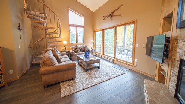 A spacious living room with a wooden staircase, a large window, and a fireplace. - Family-Friendly Escape | Balcony & Bike Path (Keystone)
