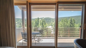 A room with a sliding glass door leading to an outdoor balcony with a table and chairs, a view of a forested hillside, and a railing. - Last Minute Holiday Rates! Great for Families, Ski Mt Views! (Keystone)