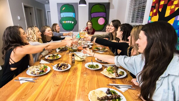 A group of people around a wooden table with various dishes, glasses, and cutlery.