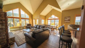 A spacious living room with a large sectional sofa, a dining area, and a kitchen with a bar. - Family Getaway | Balcony, Trails & Mountain Views (Keystone)