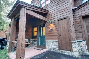 Cozy cabin with a green door and a small porch area.