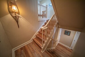 A wooden staircase with white railings and a wall-mounted light fixture.