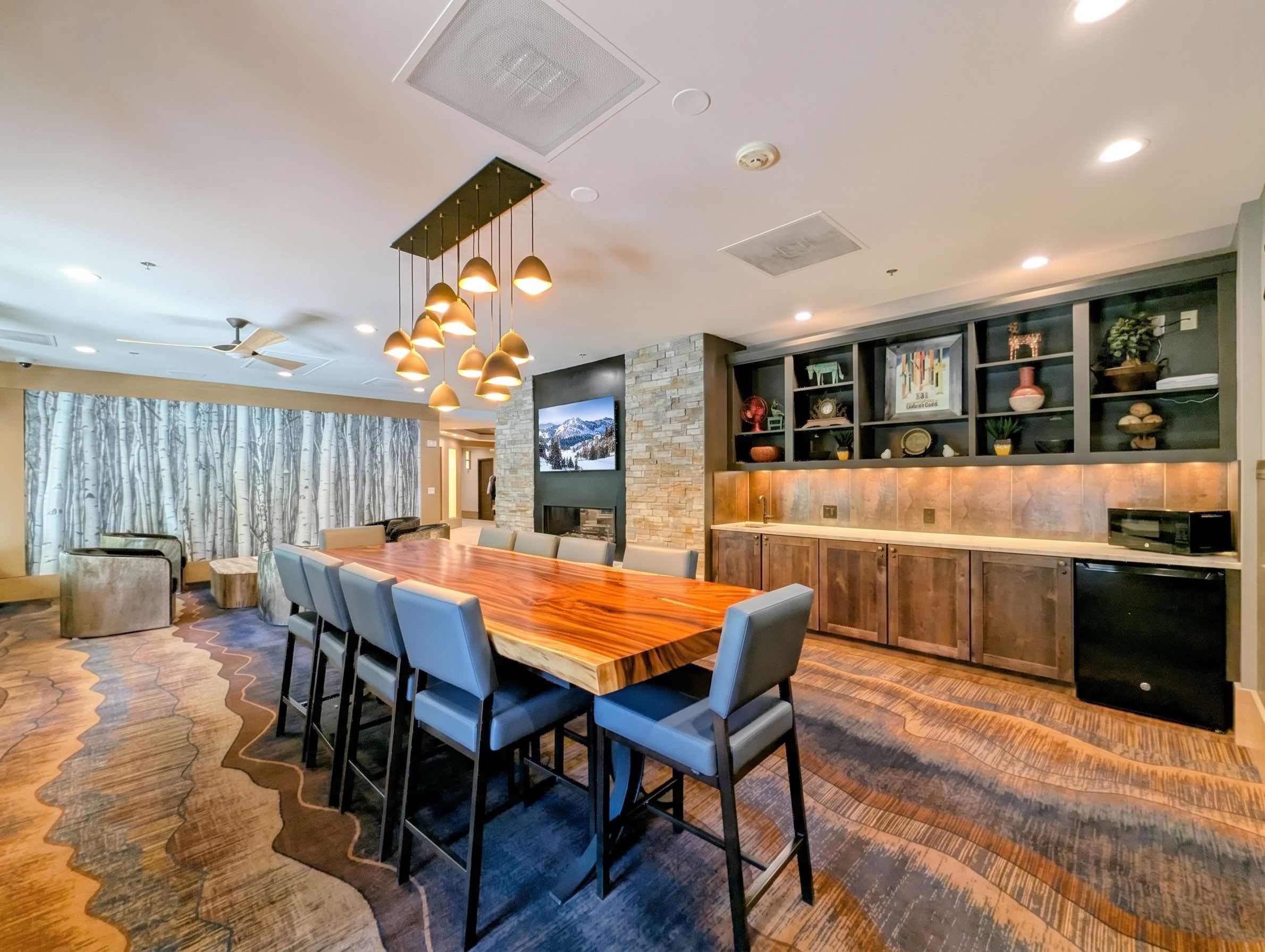 A modern kitchen with a built-in microwave, a dining area with a large wooden table and chairs, and a stone accent wall.