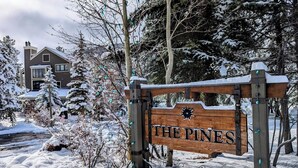 A wooden sign with "THE PINES" written on it, surrounded by snow-covered trees and a house in the background. - Cozy Condo w/Wood Fireplace & Indoor Pool/Hot Tubs (Keystone)