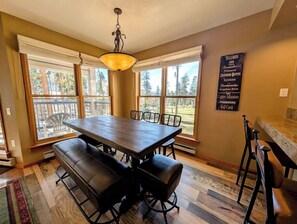 A dining area with a large wooden table, black cushioned benches, and a hanging light fixture. - Bright Updated 3B w/bunk room, Indoor Pool/Hot Tub (Keystone)