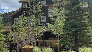 A two-story building with a dark brown exterior, multiple windows, and a stone foundation. - Keystone Summer Escape | Scenic + Pool (Keystone)