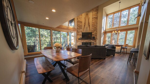 A spacious living room with a fireplace, a dining area with a wooden table and benches, and large windows offering views of the outdoors. - Updated and Perfect for Families! (Keystone)