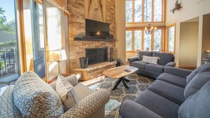 A spacious living room with a stone fireplace, large windows, and modern furniture. - Updated and Perfect for Families! (Keystone)