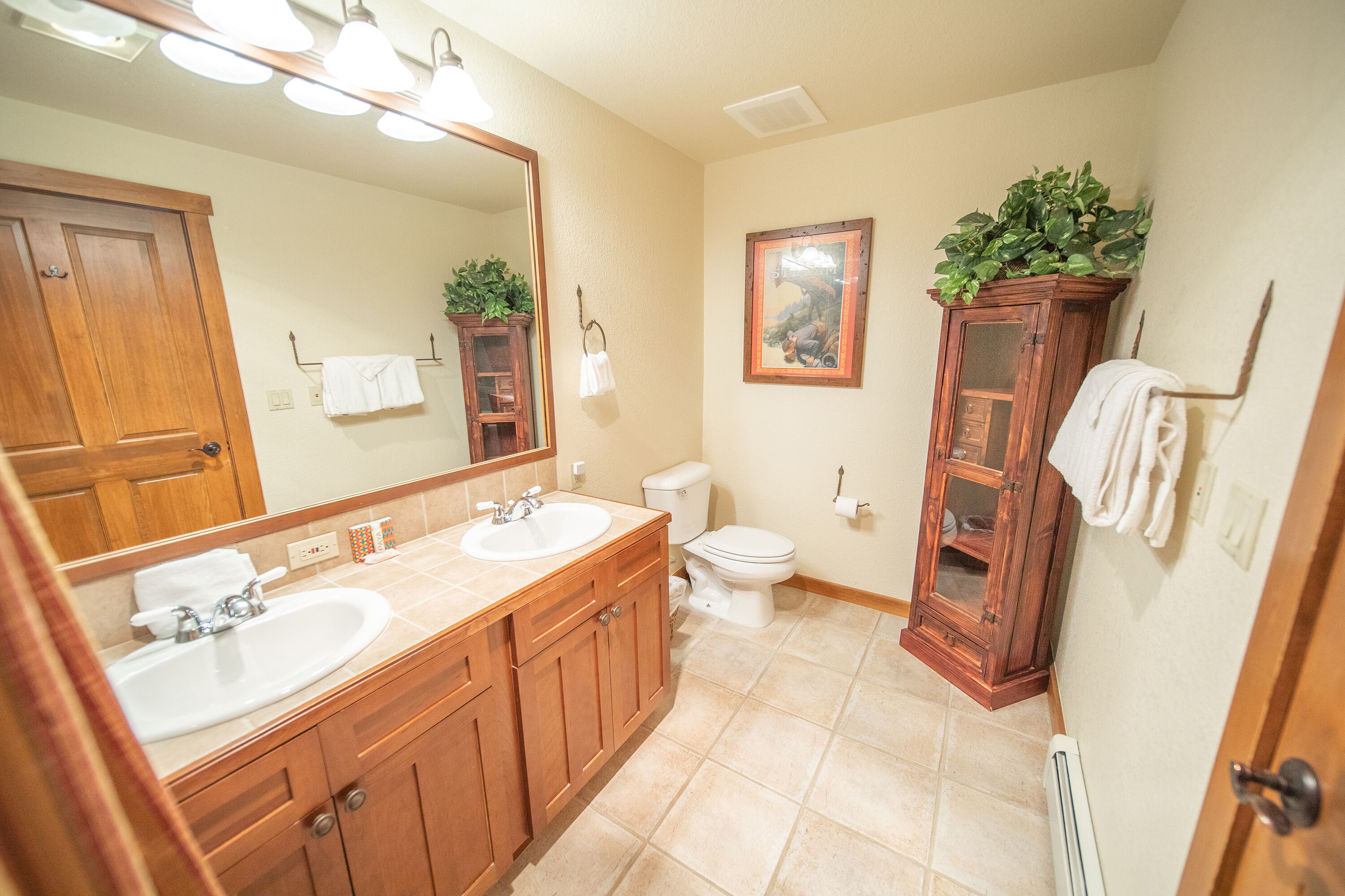 A bathroom with two sinks, a toilet, a cabinet with a mirror, and a radiator.