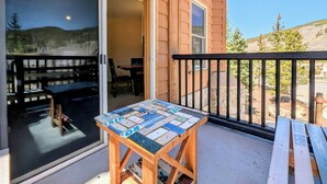 A wooden table with a mosaic tabletop on a balcony with a stone wall and a view of a mountainous landscape. - Corner Unit | Hot Tub & Village Summer Fun (Keystone)