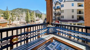 A balcony with a view of a mountain, a building with balconies, and a wooden deck. - Corner Unit | Hot Tub & Village Summer Fun (Keystone)