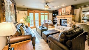 A spacious living room with a fireplace, leather sofas, a coffee table, and a bookshelf. - Mountain Retreat – Hot Tub, Pool, Balcony, Views (Keystone)
