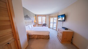 Une chambre à coucher avec un lit, une commode, un téléviseur et une fenêtre.