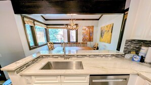 A modern kitchen with a large island, stainless steel appliances, and a view to the outdoors. - Modern Unit w/Pool & Hot Tub + 2 Parking Spots (Keystone)