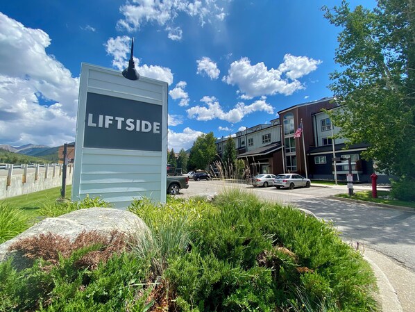 A sign with 'LIFTSIDE' written on it, a parking area with cars, and a building with a flag.