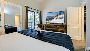 A bedroom with a large bed, a television on the wall, and a window with a view of trees. - Quiet, Outdoor Pool/Indoor Hot Tub, Shuttle (Keystone)
