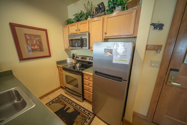 A kitchen with wooden cabinets, a stainless steel refrigerator, a microwave, an oven, and a sink. - Mountain Retreat/Hiking, Biking & Summer Action (Keystone)