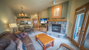 A living room with a fireplace, a television, and a stone fireplace surround.