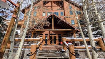 Una cabaña con fachada de madera, una entrada central con escalones y un cartel que dice "ARAPAHOE LODGE".