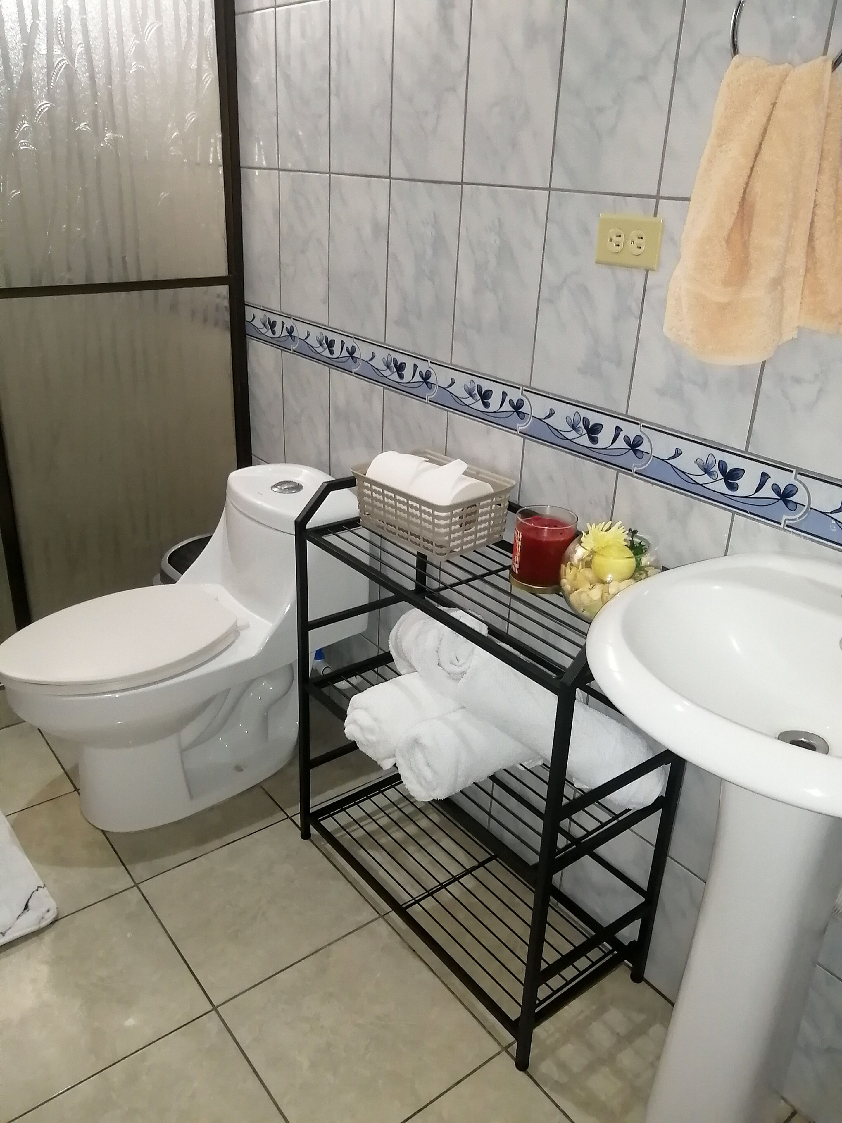 A bathroom with a toilet, a sink, and a shelf with towels and toiletries.