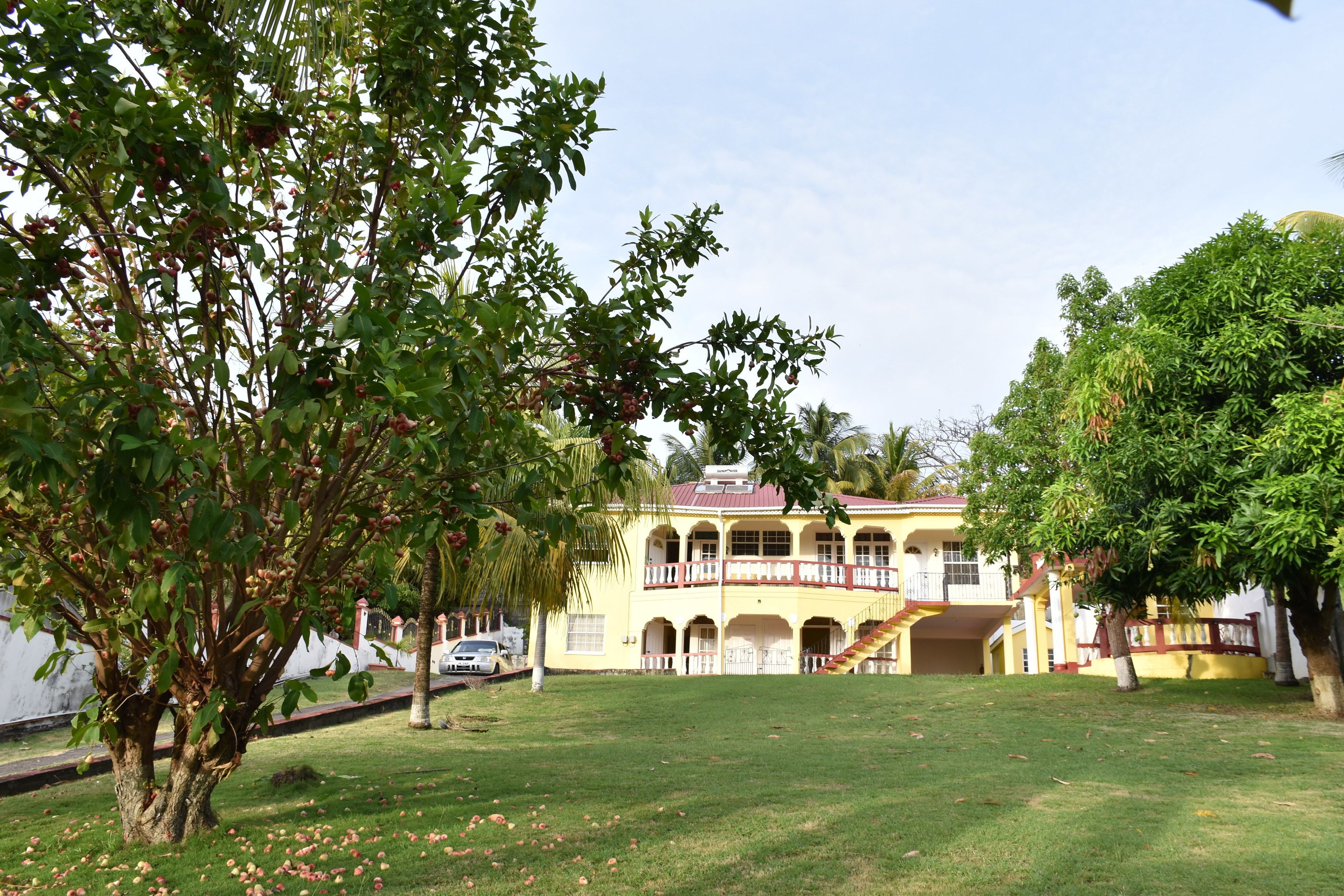 A two-story building with a balcony, surrounded by a well-maintained lawn and trees.