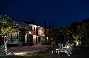 Una casa moderna de dos pisos con una entrada bien iluminada, camino de entrada pavimentado y zona de estar al aire libre.
