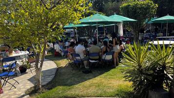 Un'area pranzo all'aperto con tavoli e sedie, immersa nel verde e alberi.