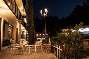 An outdoor patio with white metal furniture and a stone wall. - Hotel Real Campestre Tepetoci (Tepeji del Río de Ocampo)