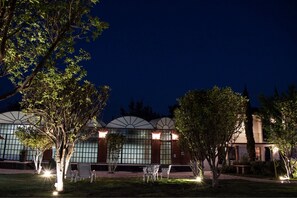 A building with large windows and a garden area with tables and chairs. - Hotel Real Campestre Tepetoci (Tepeji del Río de Ocampo)
