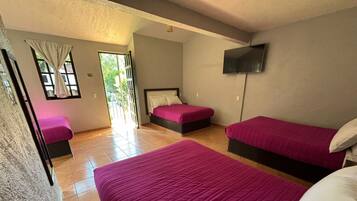 Habitación de hotel con dos camas, televisión y ventana con cortinas.