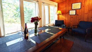 A wooden interior with a dining table, chairs, a vase with flowers, a wine bottle, and a lamp. - Amenities & Resort Access Included, Cabin 13 (Phelps)