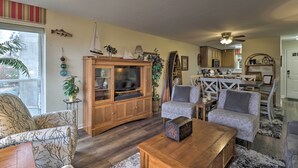 A living room with a wooden cabinet, two grey sofas, a coffee table, and a dining area with a white table and chairs. - 4 Mi to Lake: Unit w/ Pool Access in Fairfield Bay (Fairfield Bay)