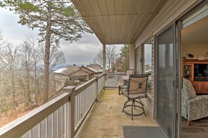 A balcony with a view of houses and trees, a chair, and a sofa.