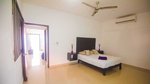 A bedroom with a bed, a ceiling fan, an air conditioner, and a nightstand with a lamp. - DEPARTMENT FOR 5 PEOPLE. EXCELLENT LOCATION (Playa del Carmen)