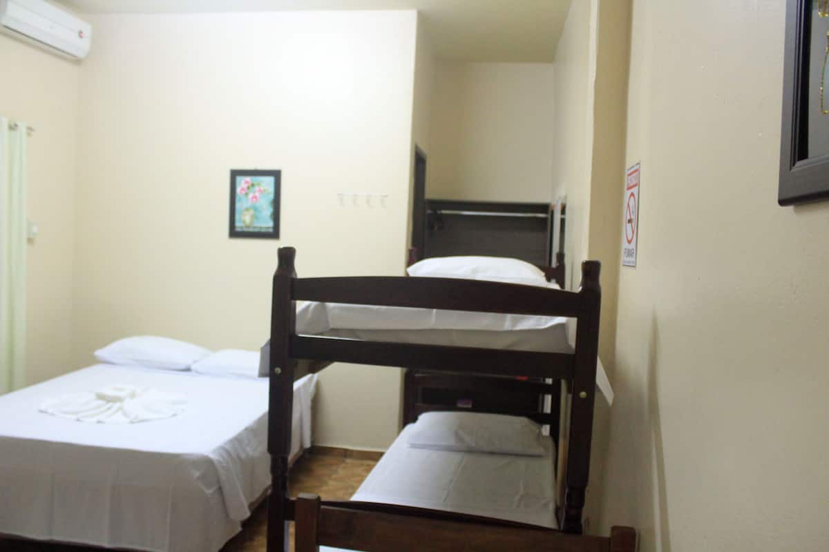 A small, clean room with two bunk beds, a single bed, and a framed picture on the wall.