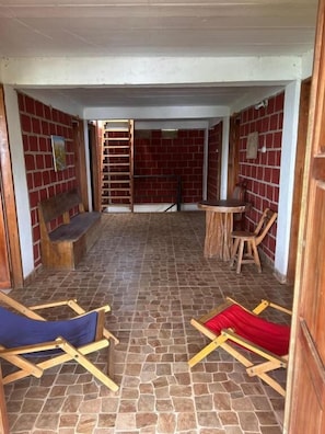 Ein Zimmer mit Backsteinwand, einer Holzleiter, einem Holzstuhl, einem kleinen Tisch und einer Bank.