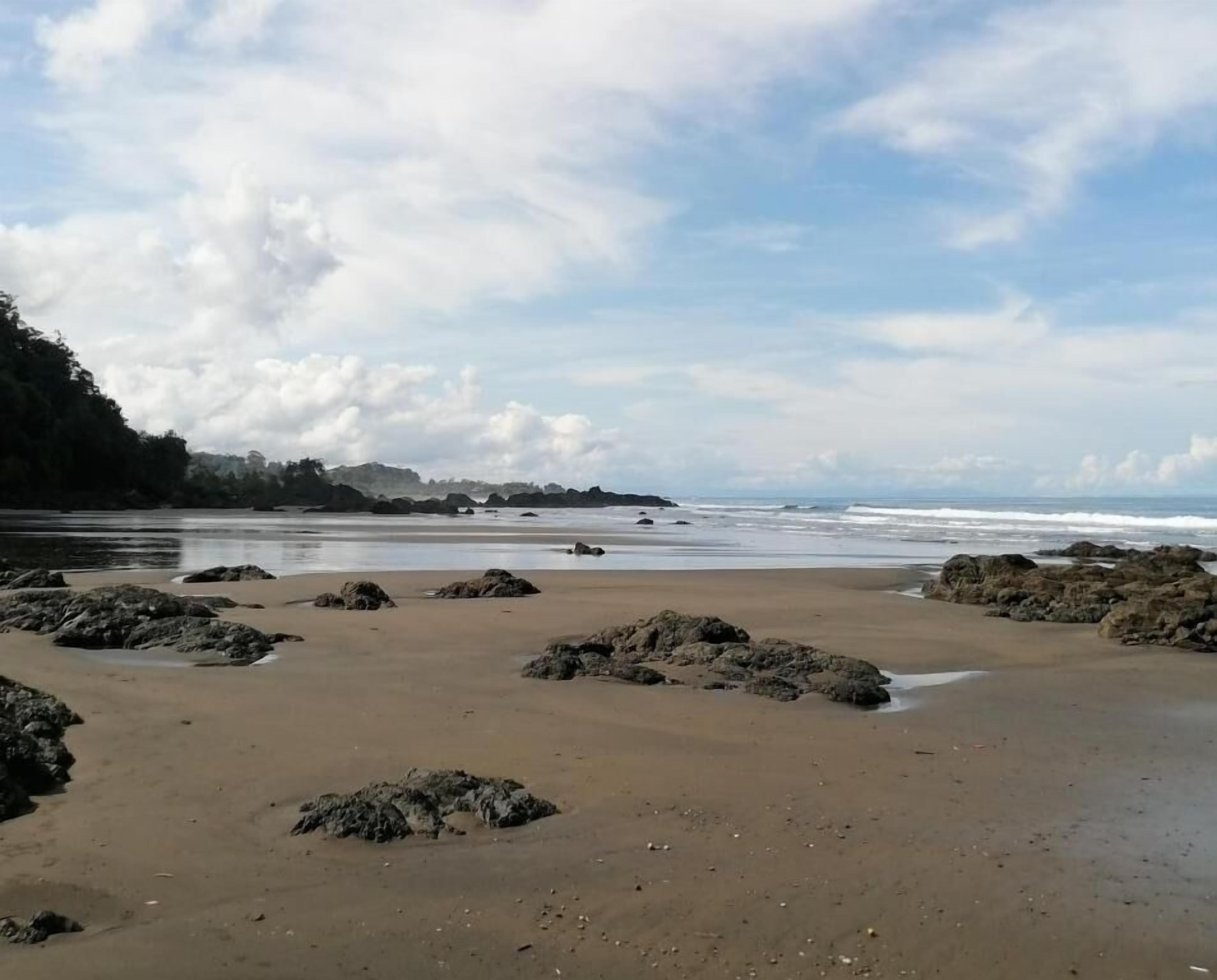 A beach with rocky outcrops and a calm sea.