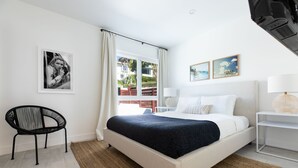 A modern bedroom with a large bed, a chair, a window with curtains, and artwork on the walls. - Avalon 2 Unit Buyout (II & IV) by AvantStay | Mins to Gaslamp! Patio w/ BQQ (San Diego)