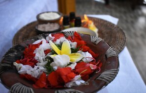 A decorative bowl filled with red and white flowers, possibly for a ceremonial purpose. - Arik's Homestay (Ubud)