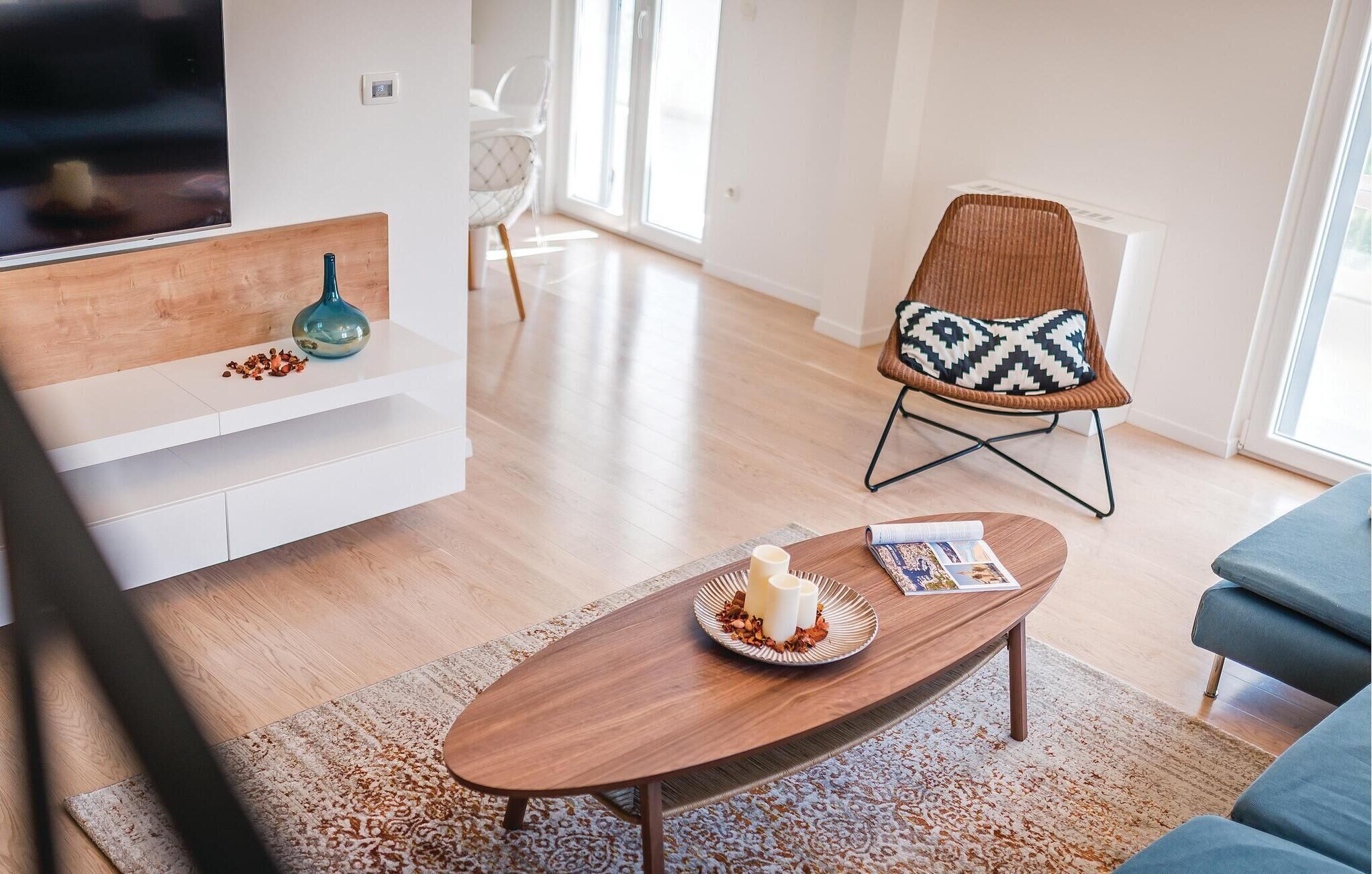 A modern living room with a wooden coffee table, a white sofa, and a patterned chair.